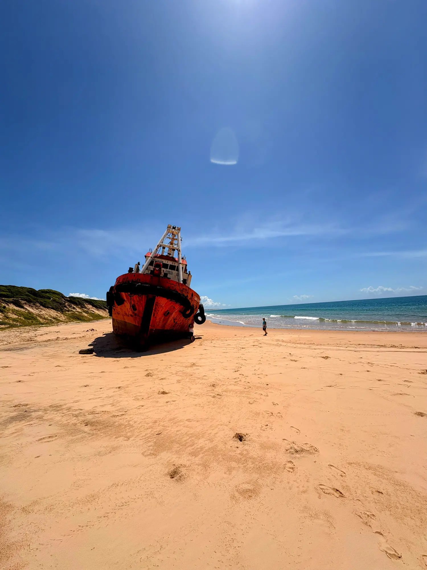 A stranded red tug on the sand